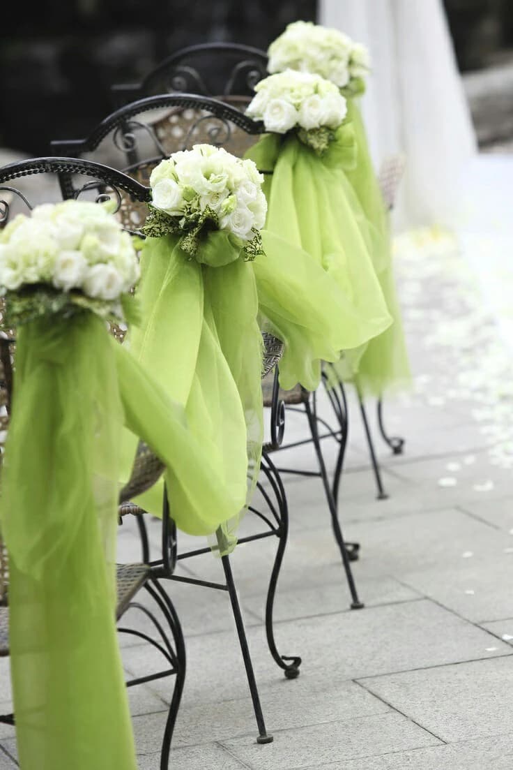 Chaises d'allée ornées de nœuds en tulle vert lime et de petits bouquets de roses blanches